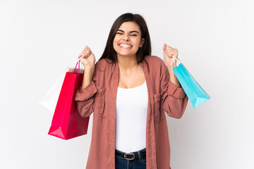 Young woman over isolated white background holding shopping bags and smiling