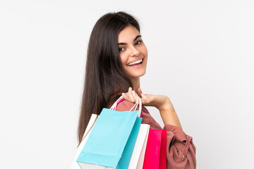 Fototapeta na wymiar Young woman over isolated white background holding shopping bags and smiling