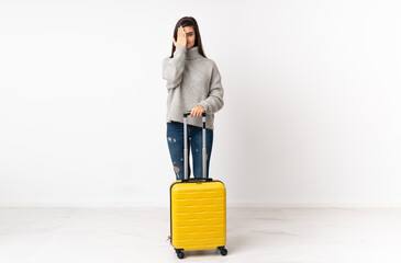 A full length body of a traveler woman with a suitcase over isolated white wall covering a eye by...
