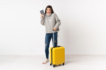 A full length body of a traveler woman with a suitcase over isolated white wall