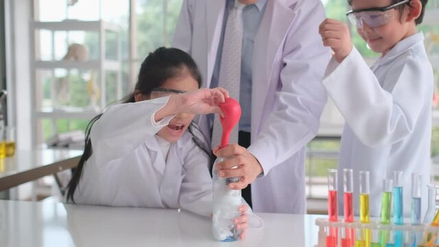 Young scientist girl pour chemical in balloon into bottle then the reaction occur creating gas and expand size of balloon with exciting and fun of children. Teacher also explain knowledge of activity.