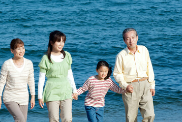 海辺を歩く３世代家族