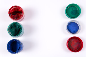 Three open jars of gouache red, green, blue and their inverted green, blue, red lids