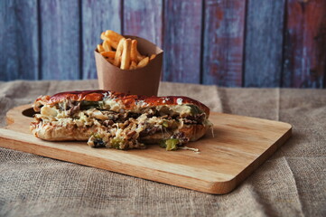 Beef cheesesteak with pommes frites on cutting board