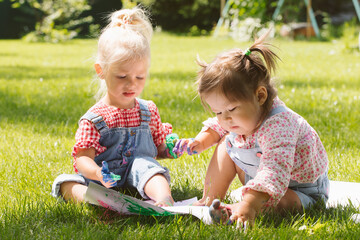 Two little girls sisters paint with finger paints