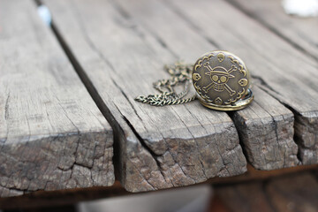 one piece vintage pocket watch with skull engraving on a wooden table