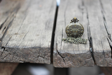 one piece vintage pocket watch with skull engraving on a wooden table