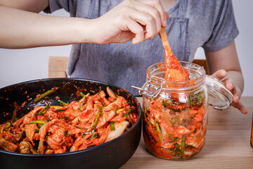 Asian woman sitting and making kimchi She is wearing protective gloves and a hat. To keep food clean. White background Korean fermented food concept made from vegetables.