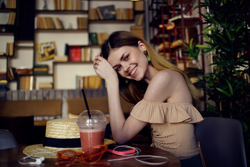 Pretty woman sits at a table in a restaurant having fun and relaxing glass with a drink