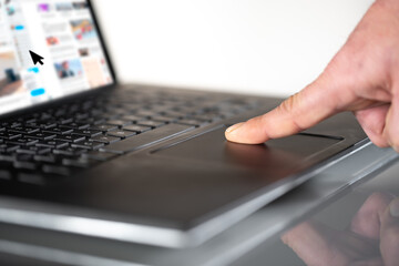 Fototapeta na wymiar Finger moving mouse pointer on laptop touchpad, profile view