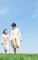 芝生を歩く母親と娘