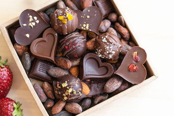 handmade chocolates in a square box with cocoa beans, grains, top view