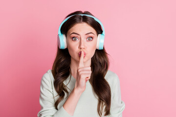 Photo of attractive lady finger covering lips showing do not tell earphones on head isolated on...