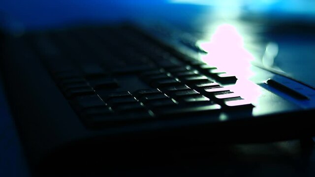 Typing on the laptop keyboard in the dark room, office. Close up, point to fingers.