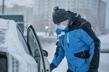 Elderly passenger in protective facemask opening door of taxi car