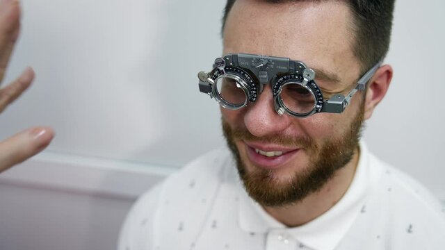 Handsome man at ophthalmology clinic. Special testing glasses with replacable lenses for vision correction on a male patient.