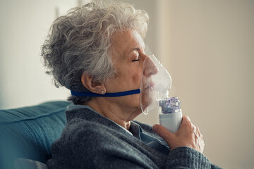 Sick senior woman making inhalation with nebulizer - obrazy, fototapety, plakaty
