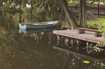 old boat on the lake on the water next to a wooden bench a place of quiet summer recreation and fishing beautiful landscape
