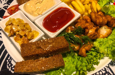 beer plate with  varied selection of beer snacks from fried bread with garlic, croutons, wings, small pickled mushrooms, french fries, herbs and small vases of sauces.