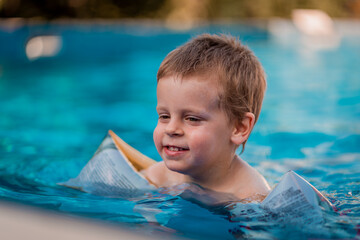 Baby boy swims independently in the pool. Little child boy learning how to swim in swimming pool