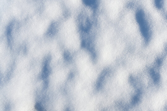 Close up of snow covered ground with uneven surface and shadows seen directly from above