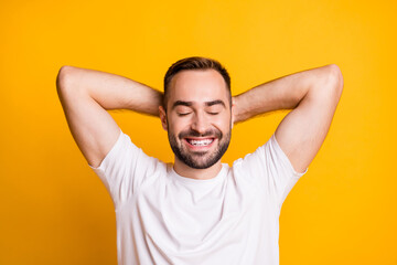 Fototapeta na wymiar Portrait of optimistic guy lie down closed eyes wear grey t-shirt isolated on vibrant yellow color background