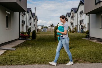 Fototapeta premium Beautiful young mother female carrying baby in baby carrier