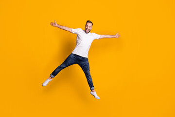 Fototapeta na wymiar Full length body size view of nice childish cheerful guy jumping having fun fooling isolated over bright yellow color background