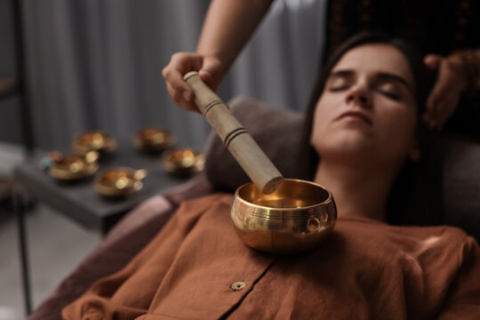 Woman at healing session with singing bowl in dark room
