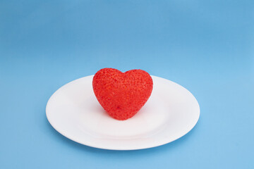 Fototapeta na wymiar Red heart on a white plate on a blue background