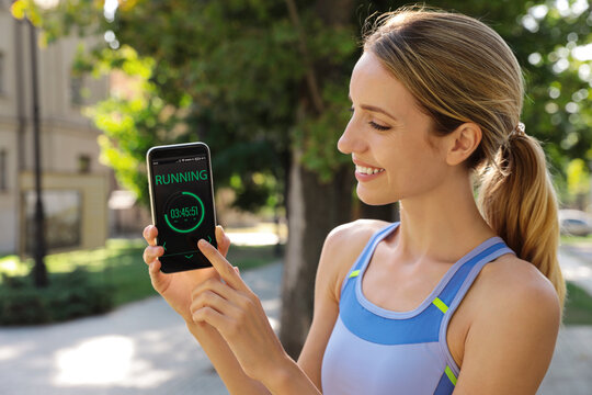 Young Woman Showing Smartphone With Fitness App On City Street