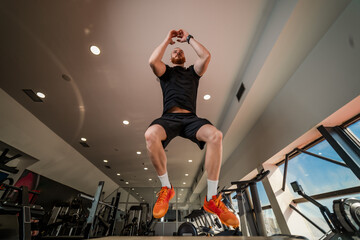 Fototapeta na wymiar Handsome strong man in gym working out and jumping