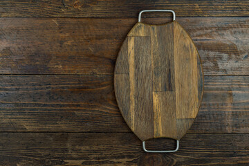 Cutting board or kitchen board on a wooden background. Space for text.
