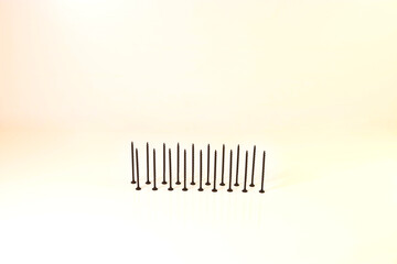 Self-tapping screws for wood surfaces, standing on hats, on a light background. Components for construction and repair. Metal fasteners.