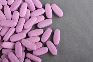 Obraz na płótnie Canvas Heap of pink medical pills on a gray background. Health concept.