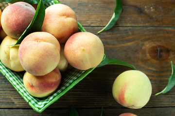 Ripe peaches in basket on wooden background. Home harvest from your own garden.
