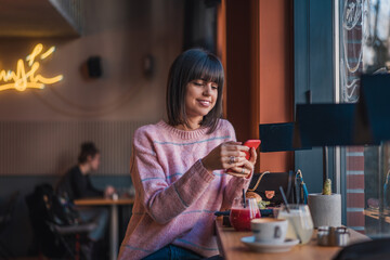 Beautiful happy female in cafe using mobile phone