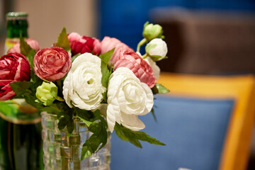 bouquet of artificial flowers in vase on table in cafe with blurred background