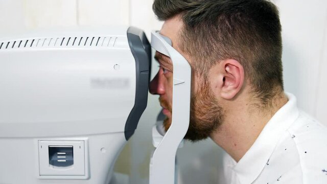 Male patient in ophthalmology clinic checks eyesight on special modern equipment. Selective focus on man`s face.