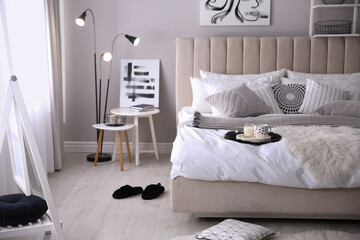 Cozy bedroom interior with cushions and striped blanket