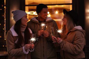 Group of happy friends with sparklers and champagne at winter fair