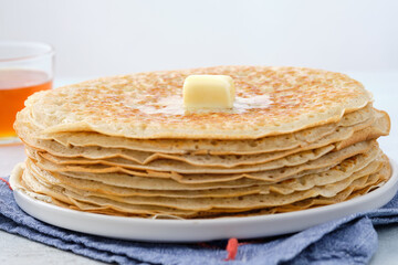 Crepes, thin pancakes with honey and butter on a white plate. Close up.