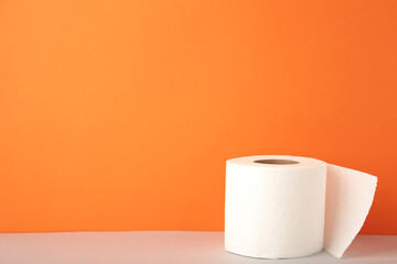 Toilet paper close-up on orange background with copy space.