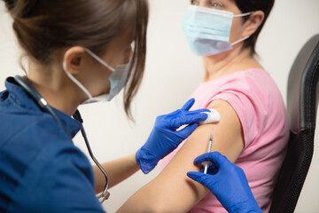 Epidemic. Close up doctor or nurse giving vaccine to patient using the syringe injected. Works in...