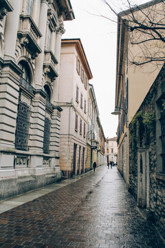 Empty medieval ancient streets in Como city, Lombardy, Italy. Vertical image of cityview with historical buildins and villas around in gloomy winter day. Selective focus