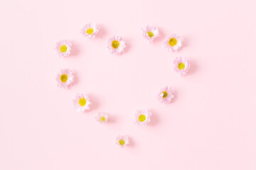 floral arrangement of chrysanthemum flowers and 1 yellow heart shaped on pink isolated background with place for text