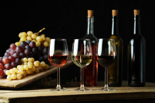Different types of wine on the rustic table with the black background