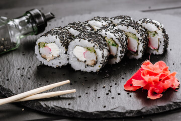 Appetizing sushi rolls with seafood on black background. Japanese food
