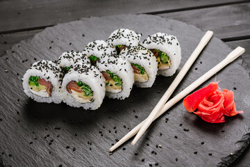 Appetizing sushi rolls with seafood on black background. Japanese food