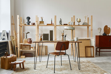 Unique artist workspace interior with stylish desk, wooden easel, bookcase, artworks, painting accessories, decoration and elegant personal stuff. Modern work room for artist. Template.